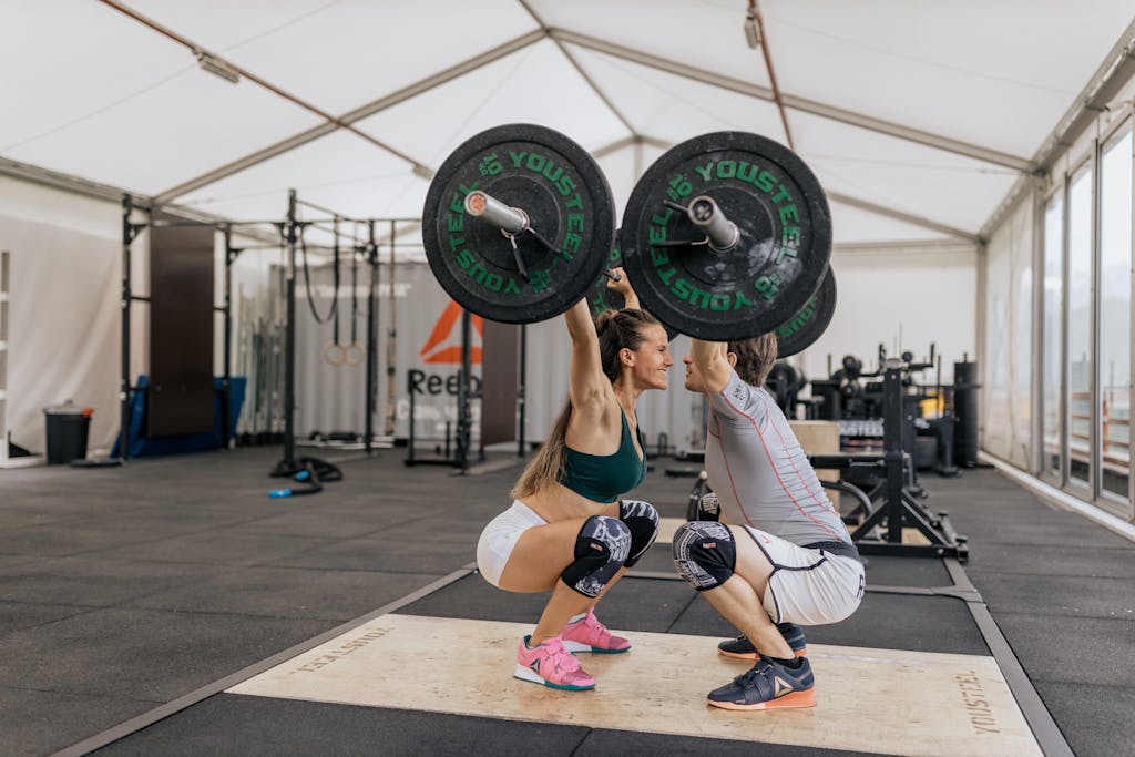 Couple Facing Each Other While Lifting Barbells