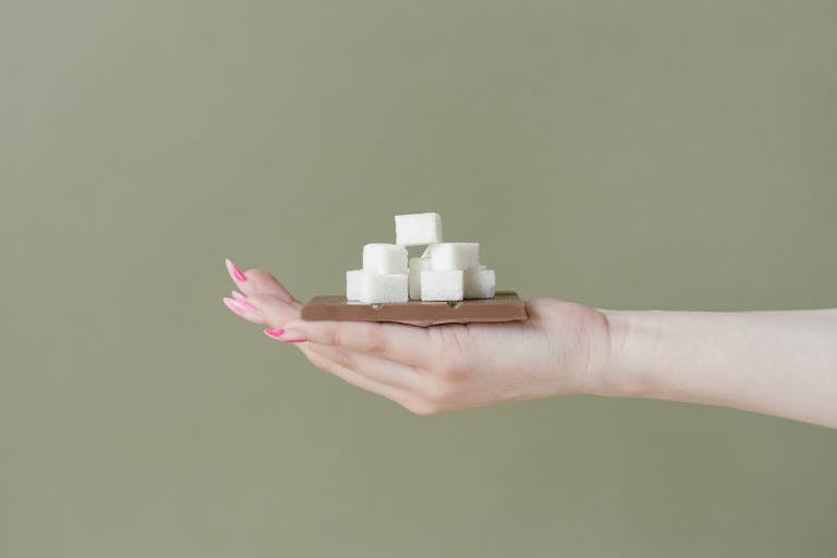 Chocolate Bar and Sugar Cubes on a Hand