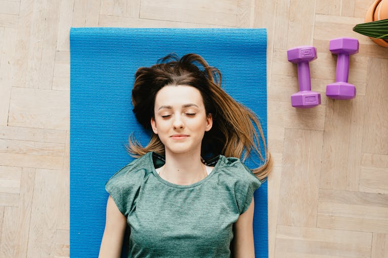 Smiling young woman meditating on yoga mat with closed eyes