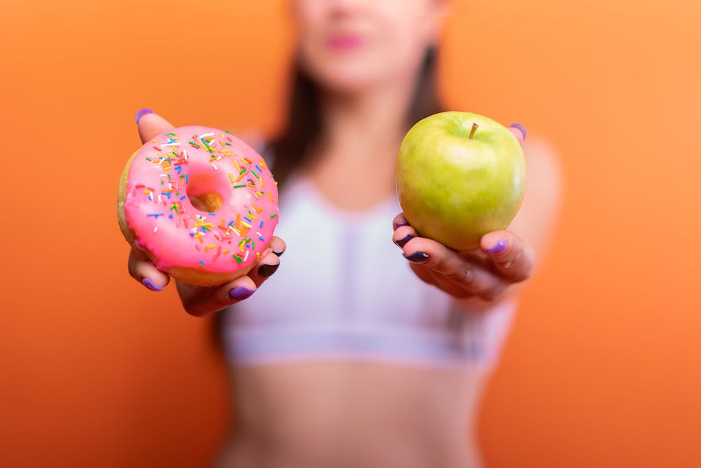 Woman Holding an Apple and a Donut